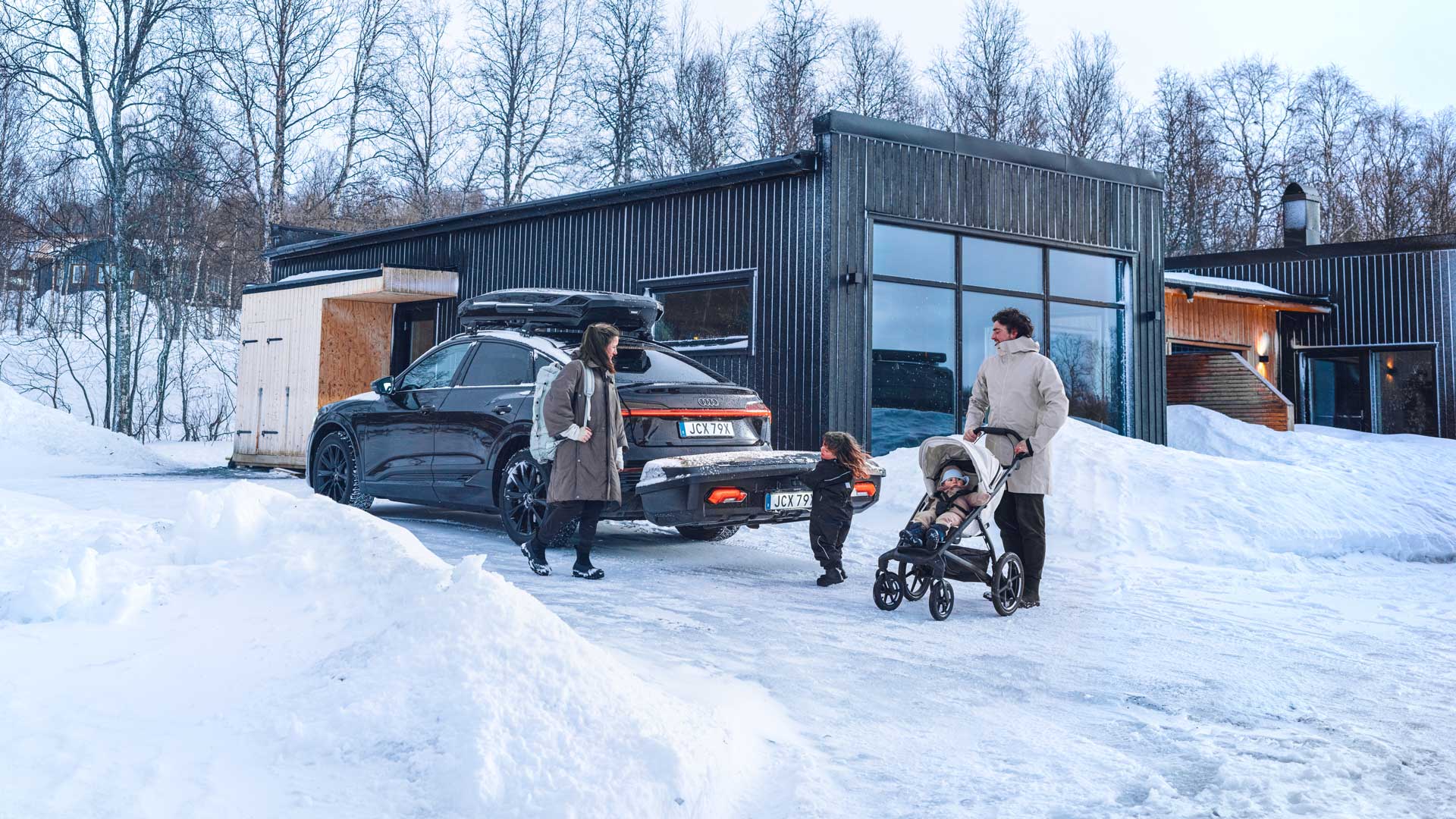Audi parkerad utanför fjällhus med monterad Thule Arcos XL på dragkroken